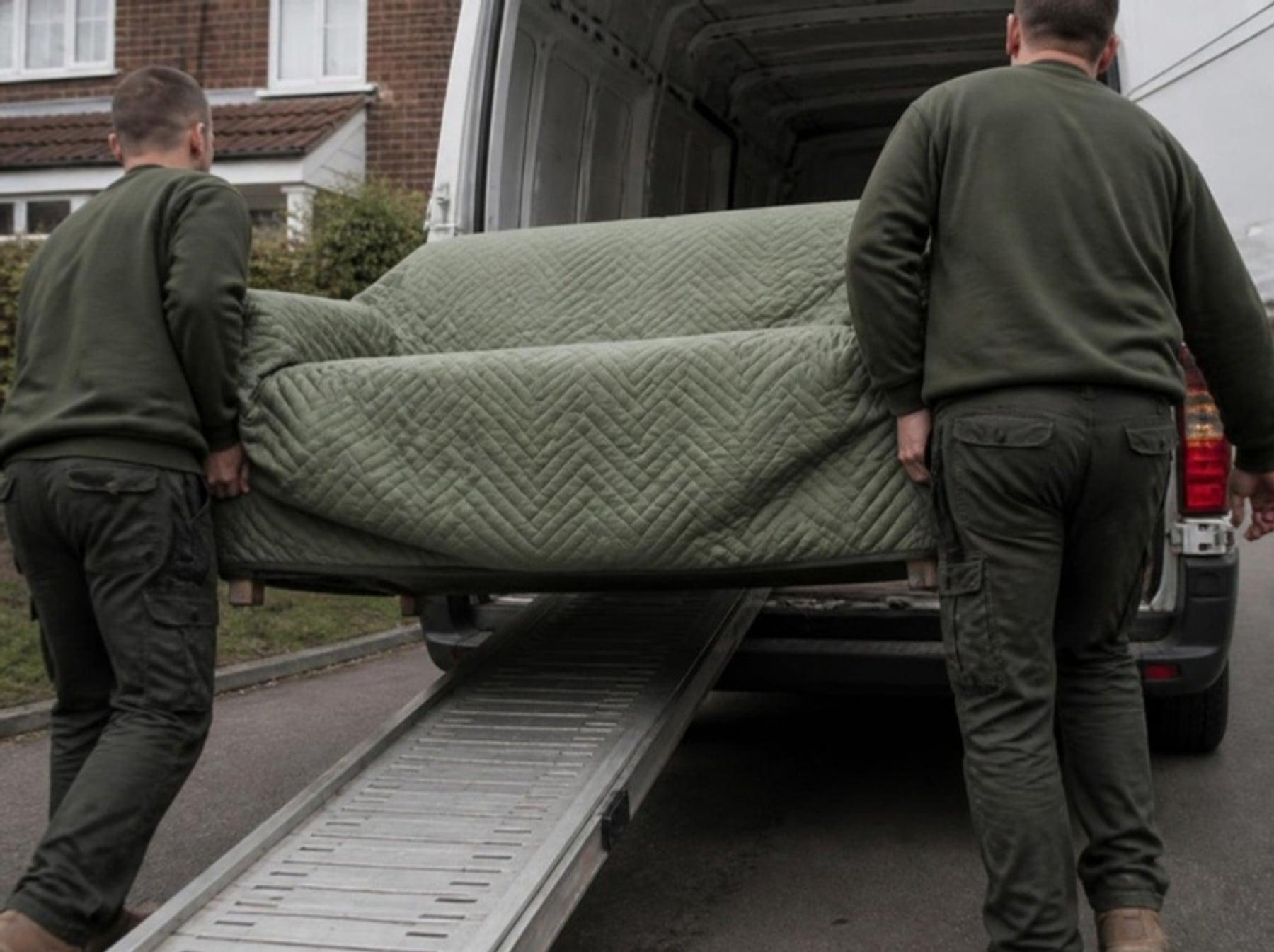 A sofa being carefully wrapped and loaded into a removals van